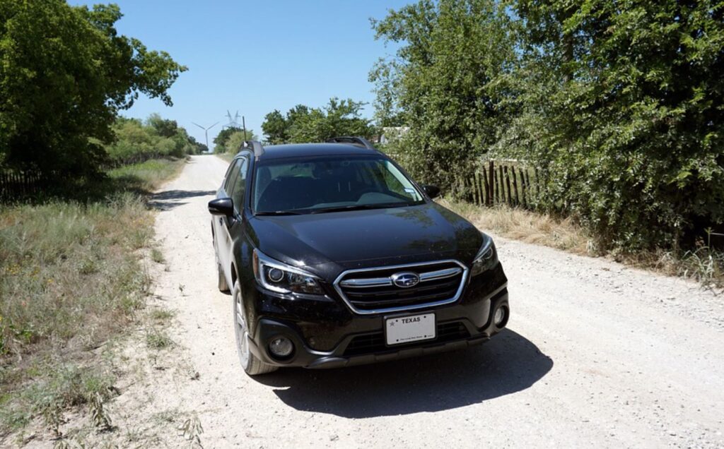 Un uomo guida la sua Subaru Outback completamente distrutta usando solo un piccolo foro nel parabrezza per vedere la strada